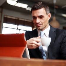 Businessman drinking coffee and reading news in cafe